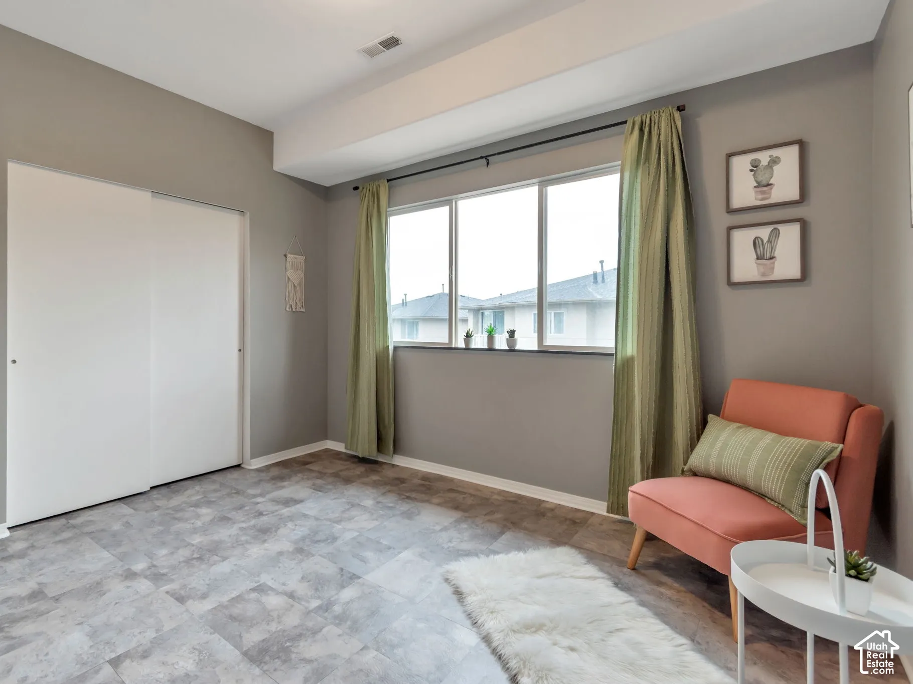 Room featuring grey-toned stone-style flooring, a large triple-pane window with a sill, and a built-in sliding-door closet