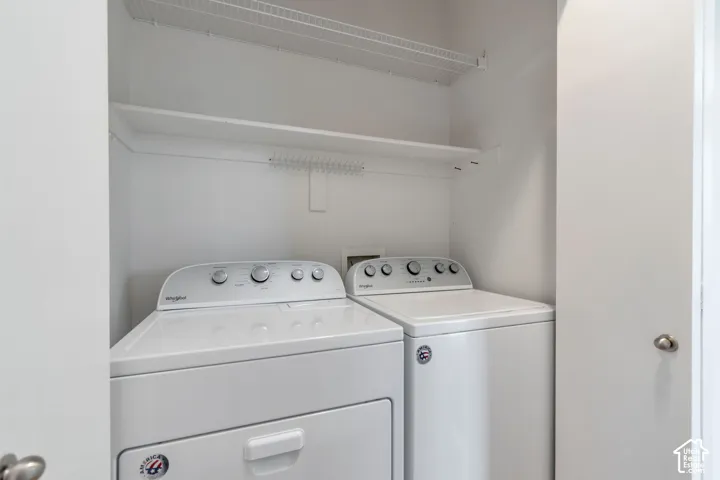 Laundry closet featuring a pair of top-load washer and dryer units, a fixed wood shelf, and an overhead wire storage rack