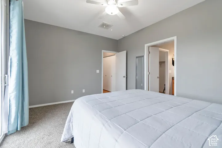 Neutral-toned interior featuring wall-to-wall carpeting, a ceiling fan with integrated lighting, and multiple interior door access points