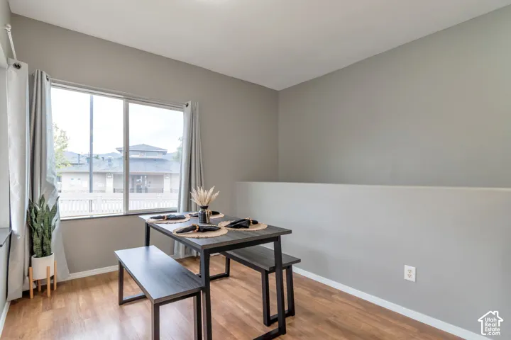 Neutral interior space featuring wood-finish flooring, a half-wall partition, and a large sliding window with natural light