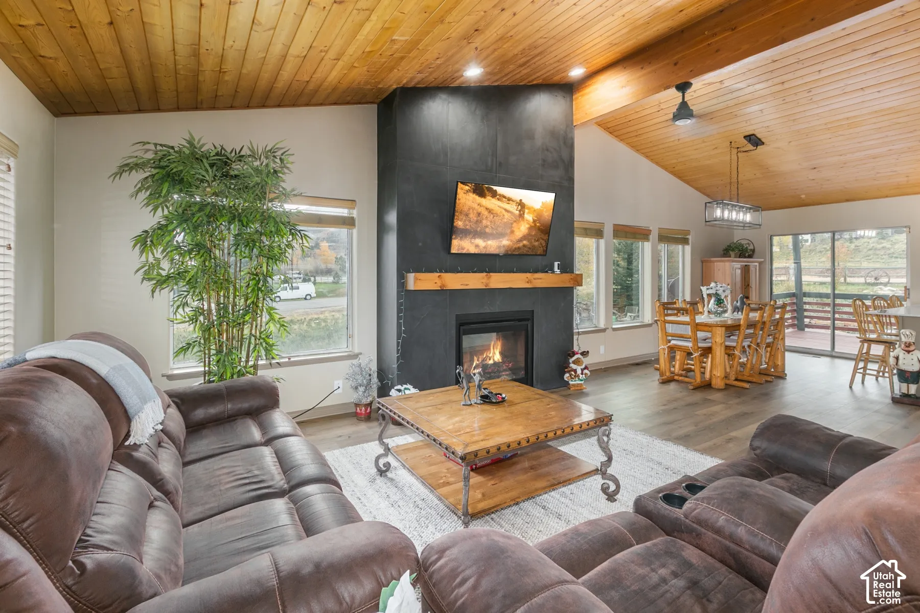 Vaulted wood-plank ceiling, floor-to-ceiling dark stone fireplace with a thick timber mantel, and wood-finish flooring