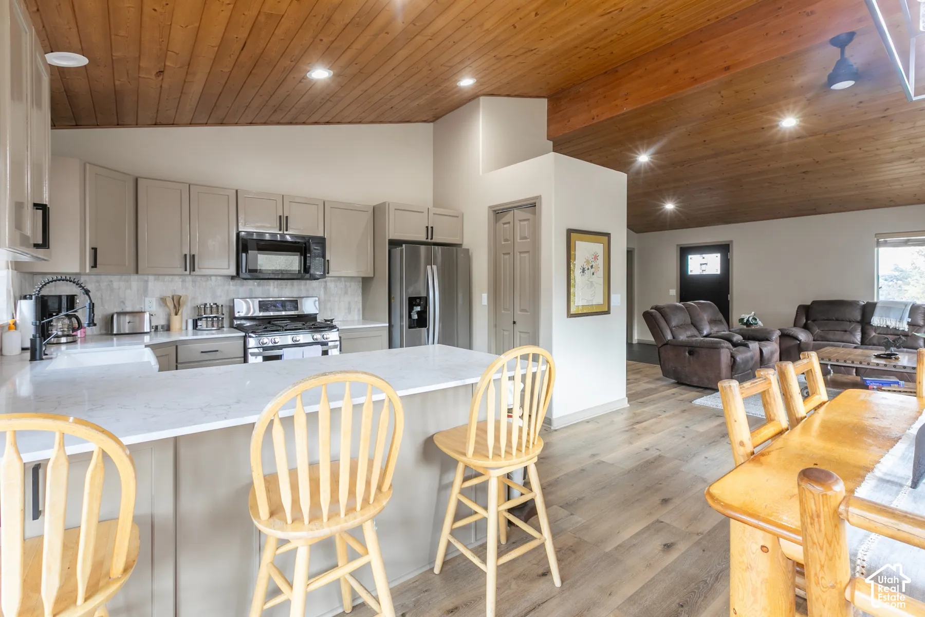 Kitchen featuring stone countertops, cabinetry with matte black hardware, stainless steel appliances, wood-plank ceiling, and wood-finish flooring