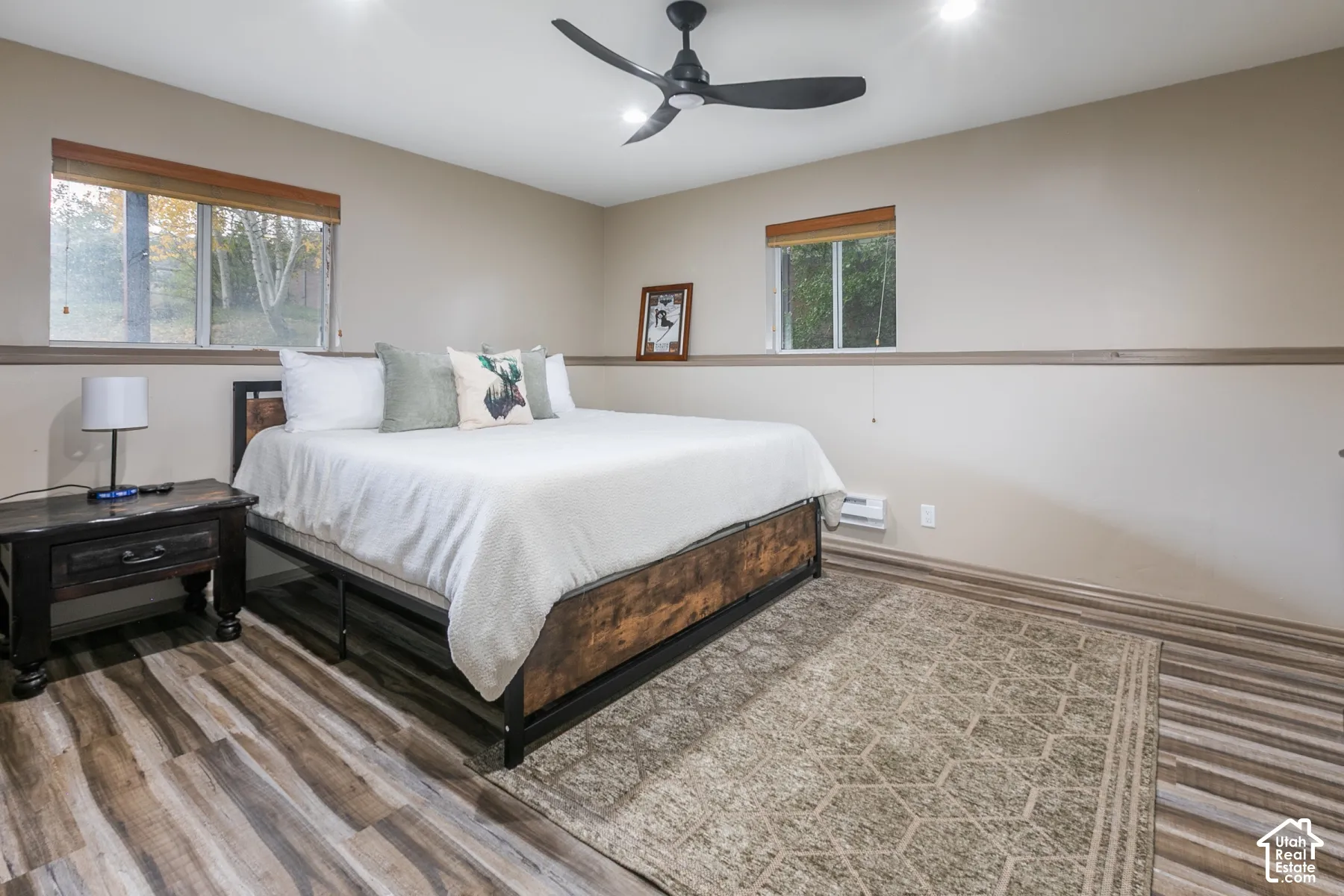 Wood-finish flooring, matte black ceiling fan, recessed lighting, and wall-mounted chair rail molding