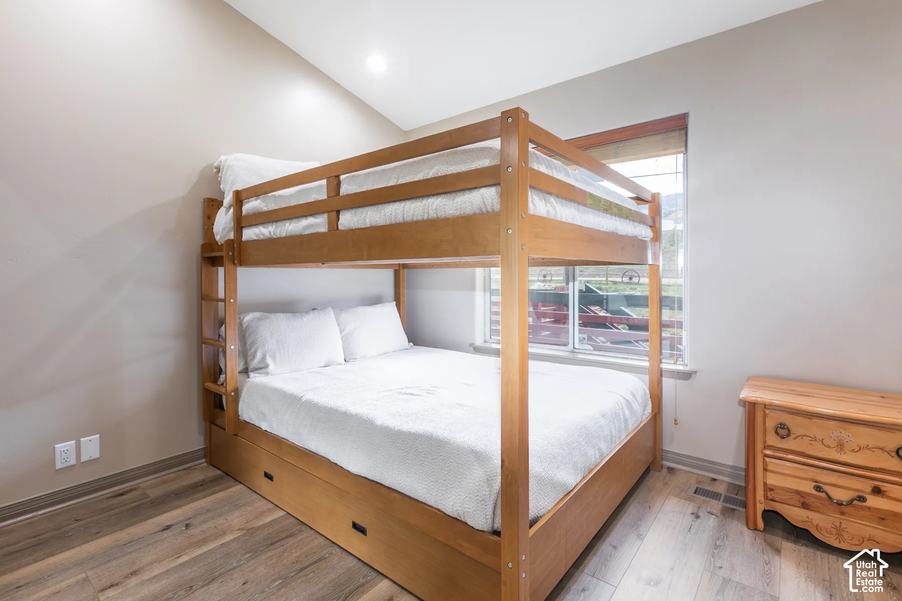 Vaulted ceiling, wood-finish flooring, and natural light via window