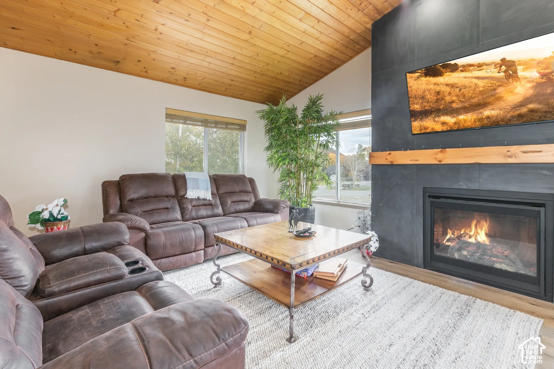 Vaulted ceiling with tongue-and-groove wood paneling, floor-to-ceiling stone-tiled fireplace surround, and natural wood mantel