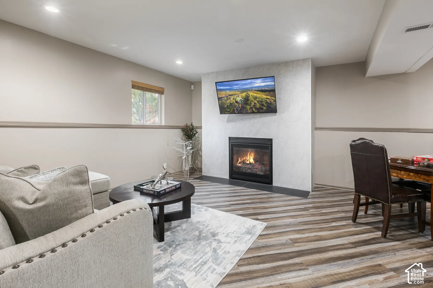 Fireplace with stone-style surround, hearth, wood-finish flooring, recessed lighting, and chair rail molding