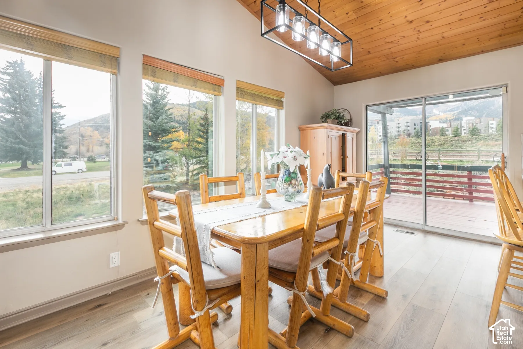 Vaulted wood-plank ceiling, wood-finish flooring, metal industrial-style pendant lighting, large windows, and sliding glass door
