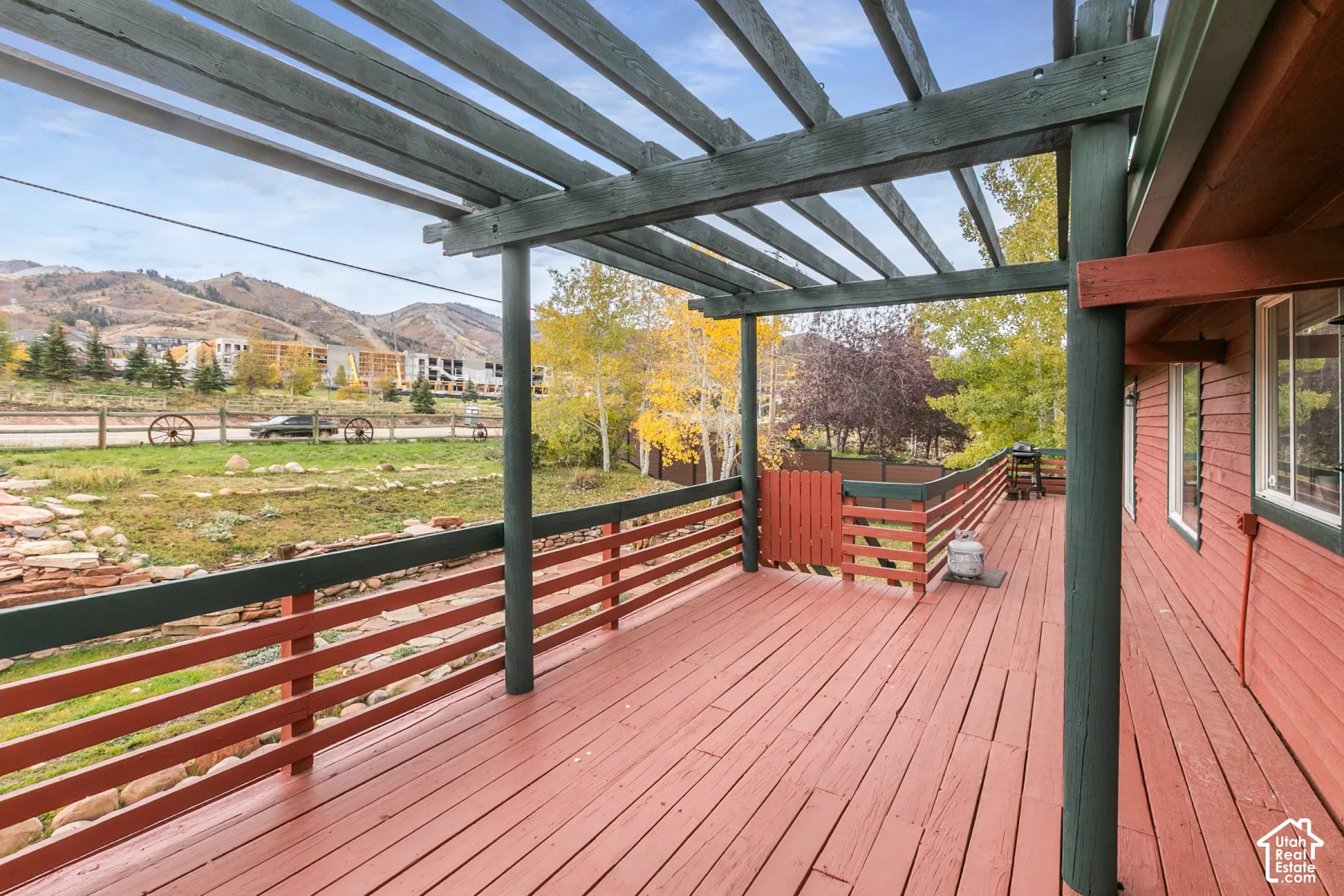 Expansive wooden deck featuring a pergola, horizontal slat railing, and mountain backdrop