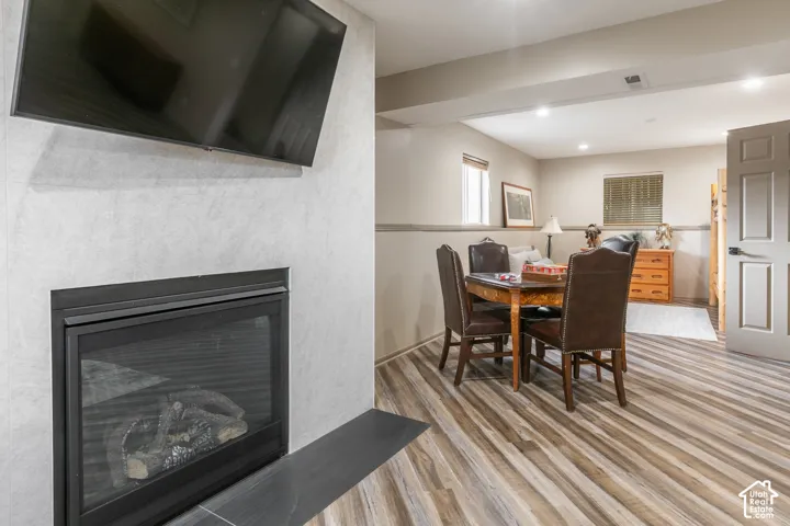 Fireplace featuring a stone-tile surround, black metal mantel, recessed lighting, and wood-finish flooring