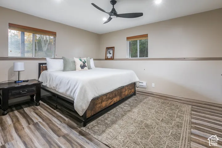 Wood-finish flooring, matte black ceiling fan, recessed lighting, and wall-mounted chair rail molding