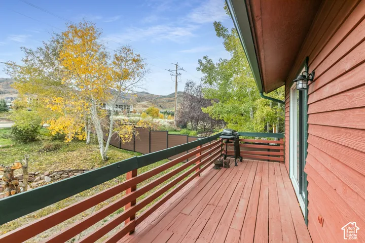 Elevated wood-plank deck featuring horizontal railing, lap siding exterior, and wall-mounted outdoor lighting