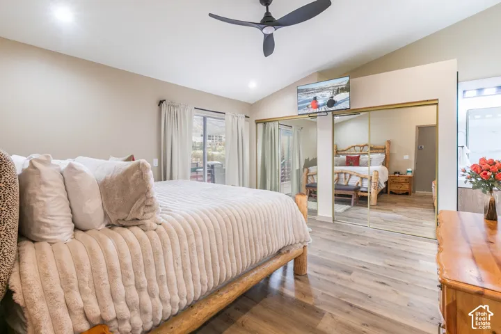 Vaulted ceiling, wood-finish flooring, ceiling fan, and mirrored sliding closet doors