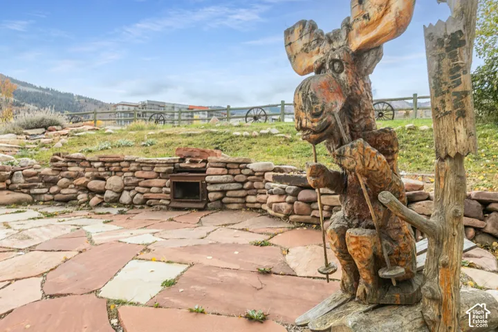 Flagstone patio featuring a stone retaining wall with a built-in fire feature and mountain backdrop