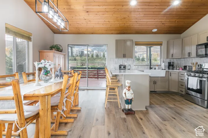 Kitchen featuring a wood-plank vaulted ceiling, wood-finish flooring, white stone-surface countertops, custom cabinetry, and an apron-front sink