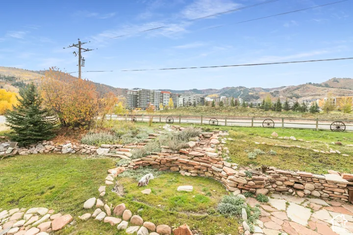 Outdoor space featuring stone terracing, flagstone hardscaping, manicured lawn, and mountain surroundings