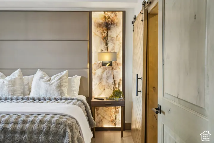 Custom upholstered wall paneling, backlit stone accent feature, wall-mounted light fixture, and wood-finished chevron sliding door