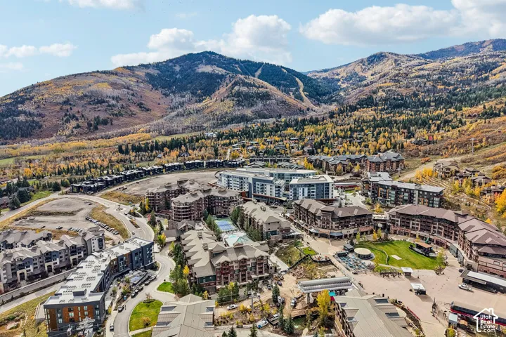 Aerial perspective featuring multi-story residential structures, established paved road infrastructure, communal swimming pool, tennis courts, and expansive mountain terrain