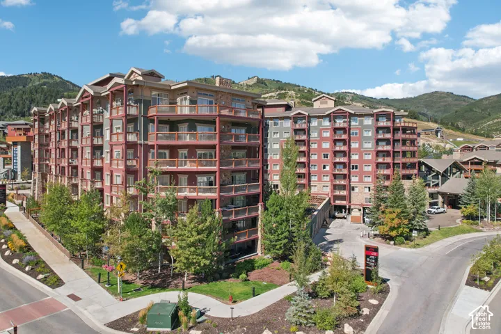 Multi-story exterior featuring stone and timber siding, expansive private balconies, and surrounding mountain scenery