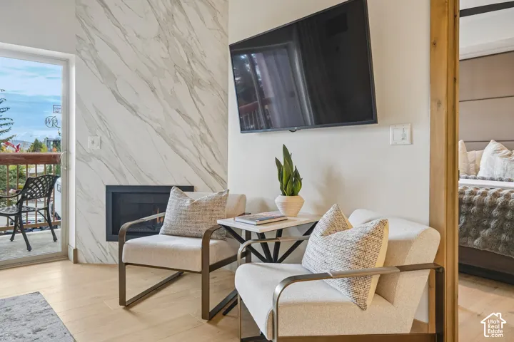Full-height stone surround fireplace, wood-finish flooring, and glass door providing exterior access