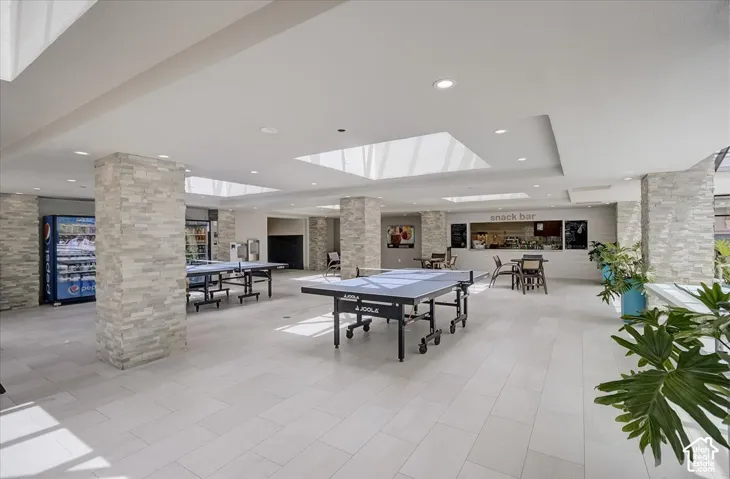 Common area featuring stone-clad structural pillars, large overhead skylights, recessed lighting, and tile flooring