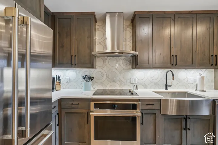 Kitchen featuring shaker-style cabinetry, stainless steel appliances, farmhouse sink with matte black faucet, quartz countertops, and decorative tile backsplash