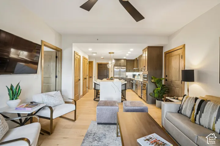 Wood-finish flooring throughout, central kitchen island with stone countertop, stainless steel appliances, recessed ceiling lighting, and wood-finish doors