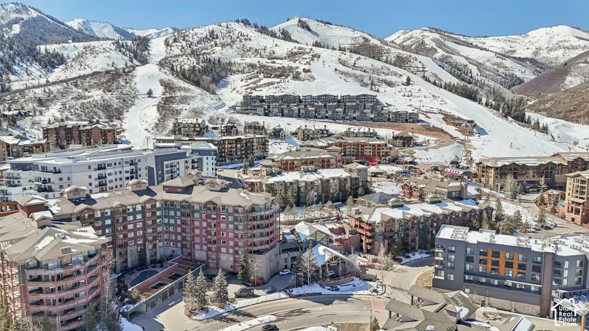 Aerial perspective of a multi-story mountain resort complex featuring stone and timber-style cladding, expansive pitched rooflines, and snow-capped mountain scenery