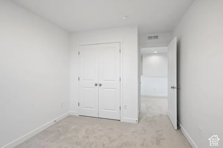Neutral-toned wall-to-wall carpeting, white interior doors with brushed nickel hardware, and dual-panel closet doors