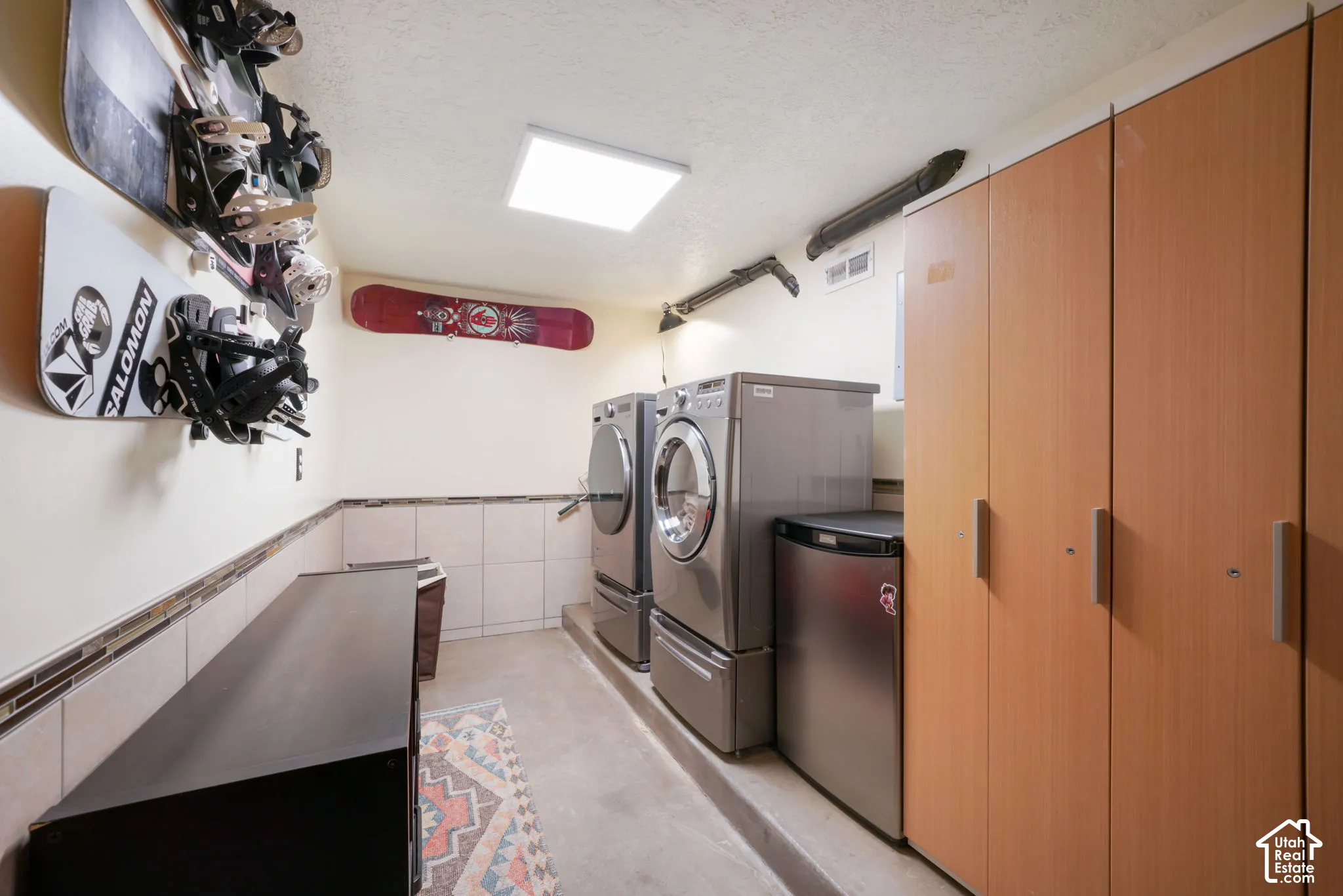 Utility area featuring floor-to-ceiling wood-finish cabinetry, ceramic wall tiling, and surface-mounted LED lighting