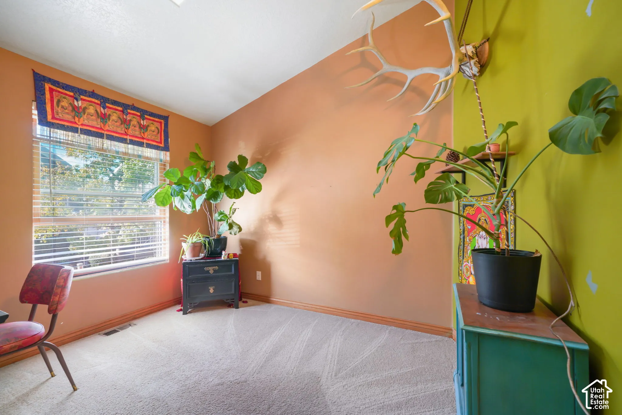 Room interior featuring neutral carpeting, a dual-tone wall finish, and a horizontal window with integrated blinds