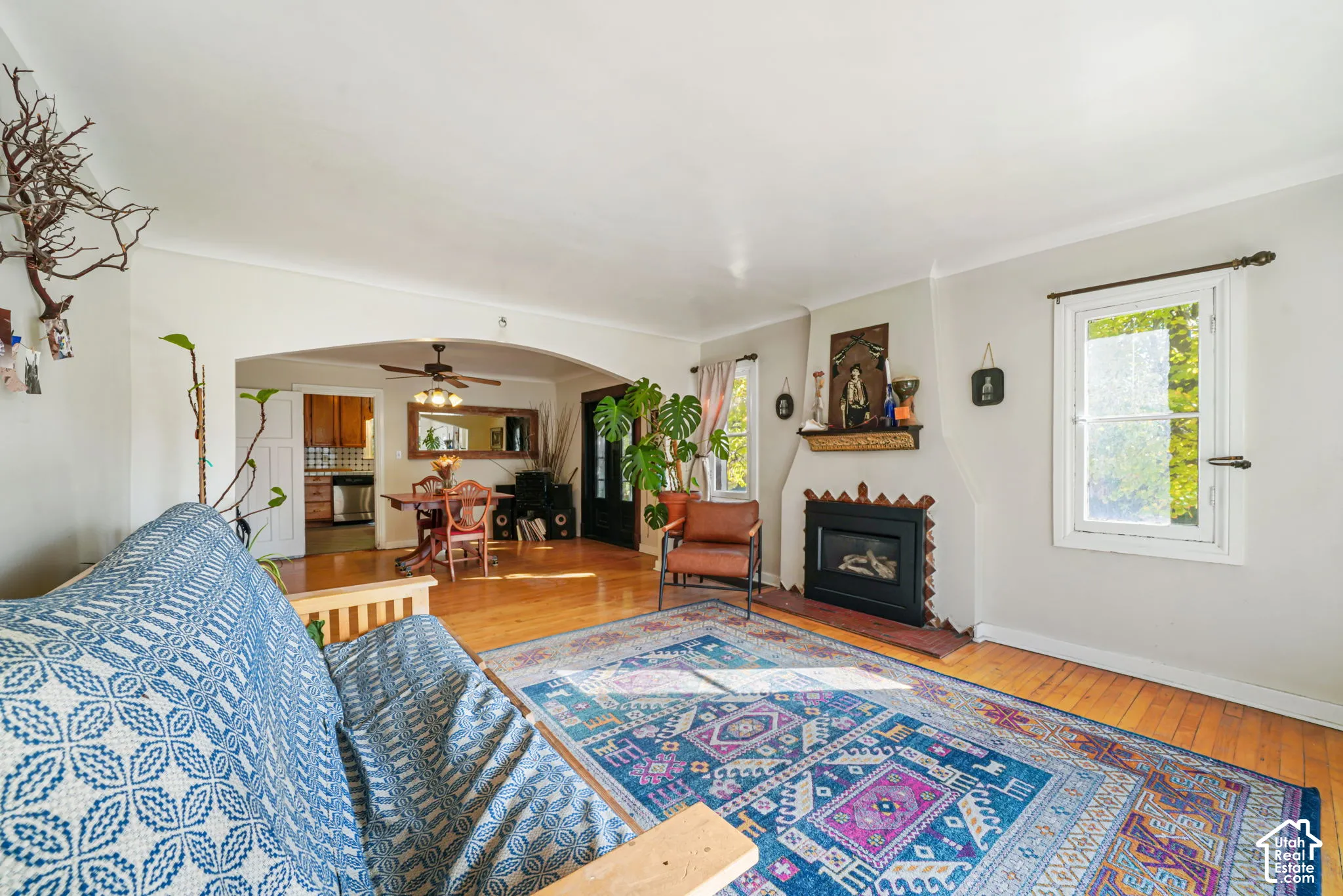Living area featuring hardwood flooring, a fireplace with a decorative mantel, and an arched architectural opening