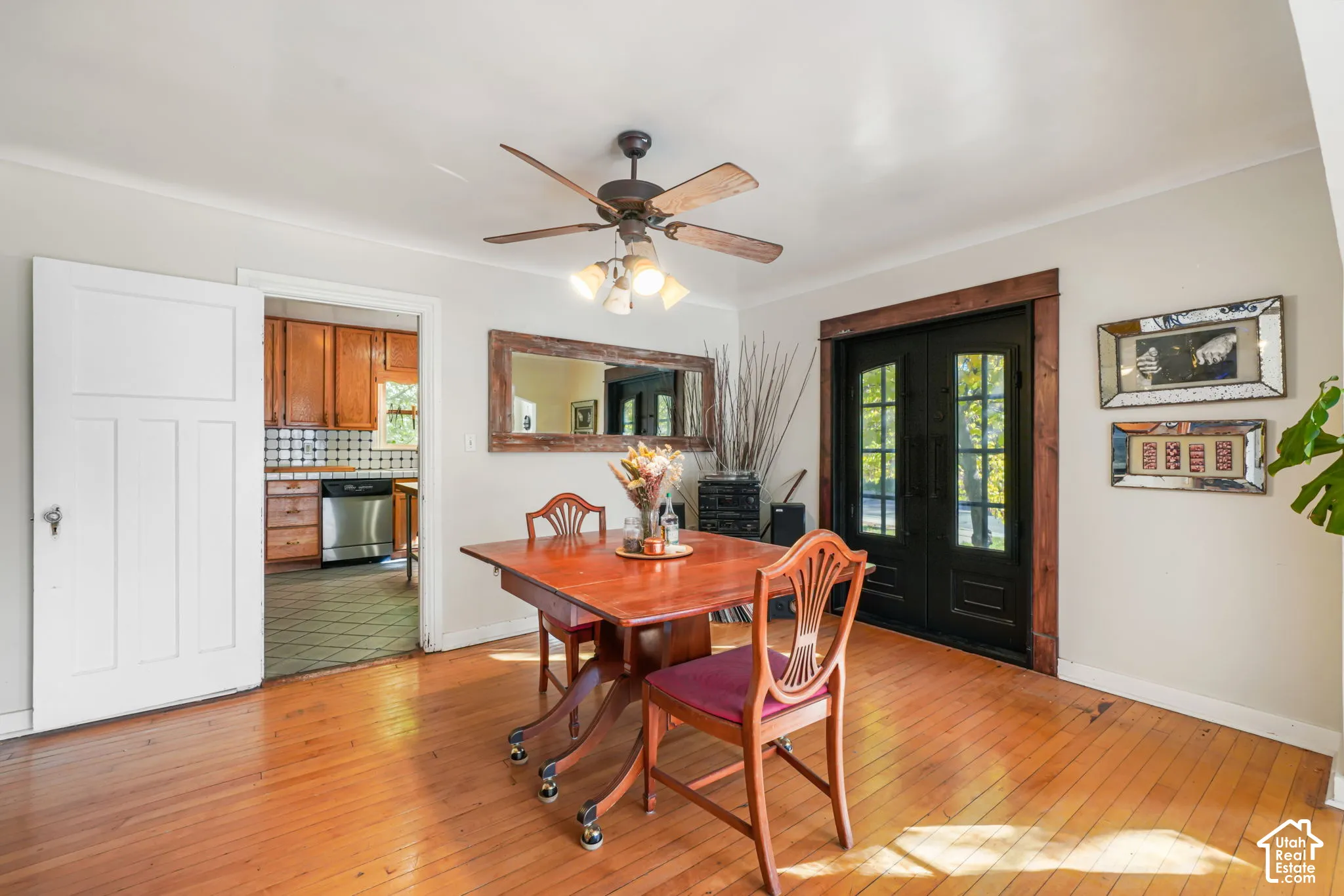 Wood-finish flooring, double-door entry with dark-stained trim, and ceiling-mounted light fixture with fan
