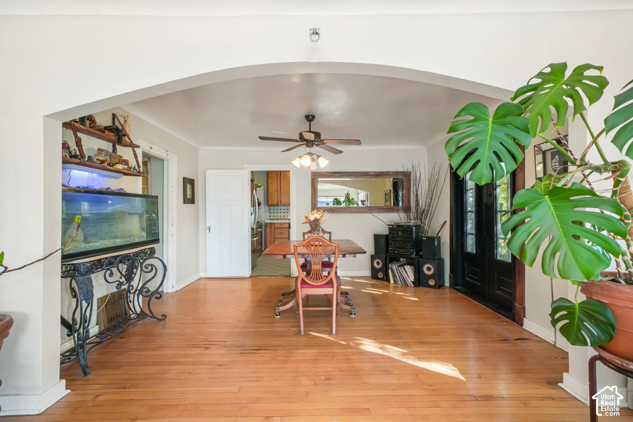 Arched entryway featuring wood-finish flooring, a ceiling-mounted light fixture with a fan, and dark-finished exterior-style glass paneled doors