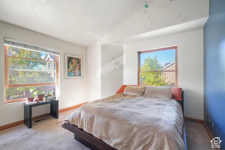Vaulted ceiling, dual windows with natural wood trim, and neutral wall tones
