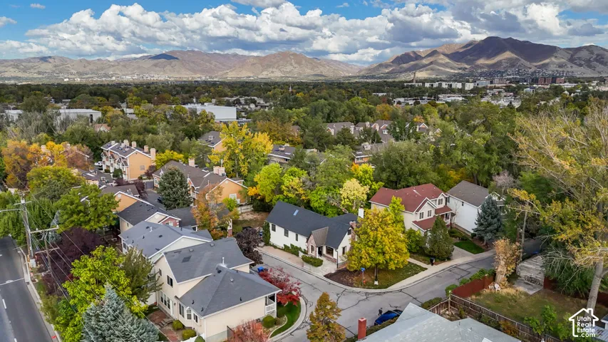 Aerial perspective featuring a neighborhood with mature deciduous trees and a prominent mountain backdrop