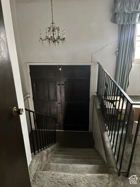 Entryway featuring double doors with a dark finish, traditional crystal-style chandelier, and black metal stair railing