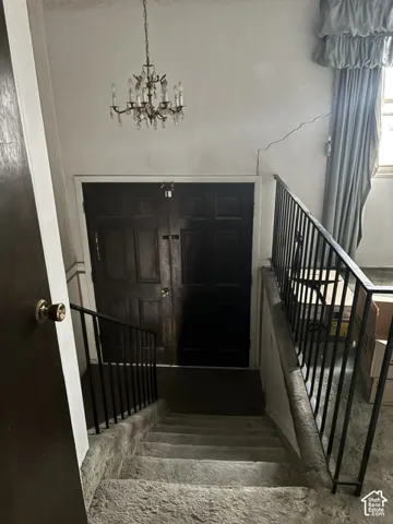 Entryway featuring double doors with a dark finish, traditional crystal-style chandelier, and black metal stair railing