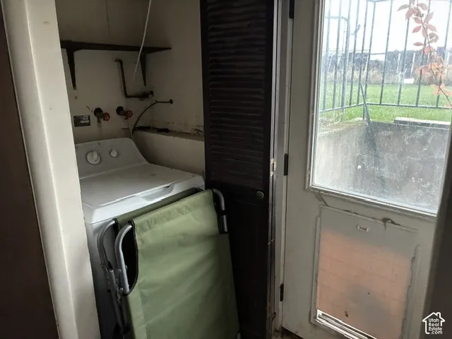 Laundry alcove featuring built-in shelving and utility connections, paired with a glass-paneled exterior door