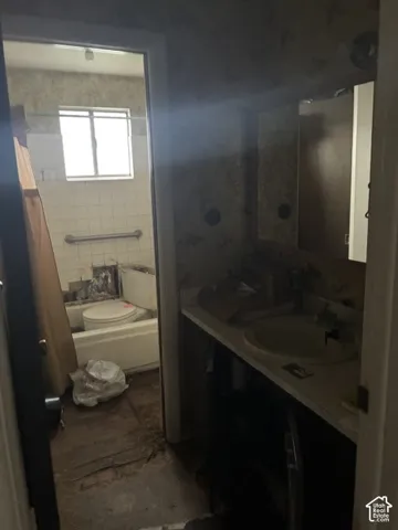 Bathroom featuring a vanity with a recessed sink, medicine cabinet, bathtub with a metal grab bar, and a window