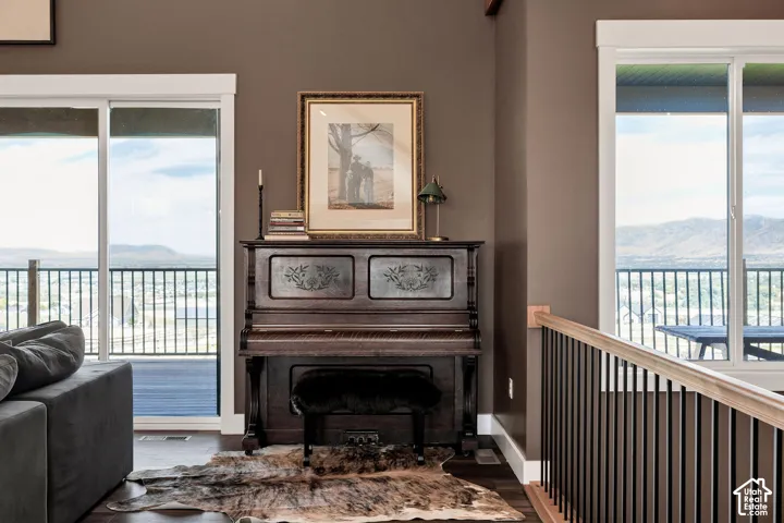 Dual sliding glass doors, metal railing with wood-finish top rail, mountain backdrop, and wood-finish flooring