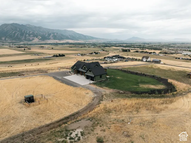 Multi-gabled residence featuring a dark-tone exterior, concrete driveway, attached multi-car garage, manicured lawn area, and mountain backdrop