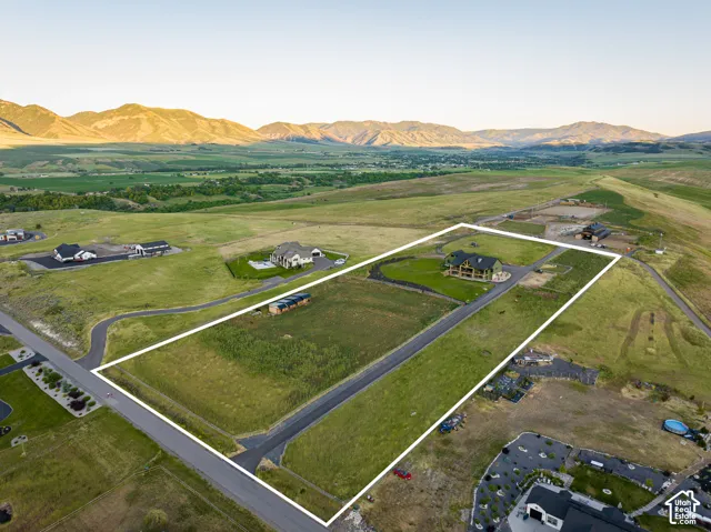 Expansive acreage featuring a paved driveway, natural topography, and a prominent mountain backdrop