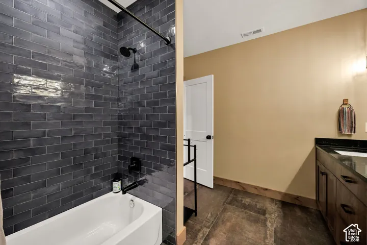Bathroom featuring a deep soaking tub with matte black fixtures, charcoal subway tile surround, dark wood vanity with a solid surface countertop, and large-format tile flooring