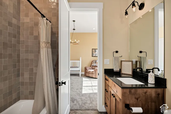 Bathroom featuring a vanity with dark countertop and wood-finish cabinetry, matte black fixtures, full-length mirror, and tile-surround tub