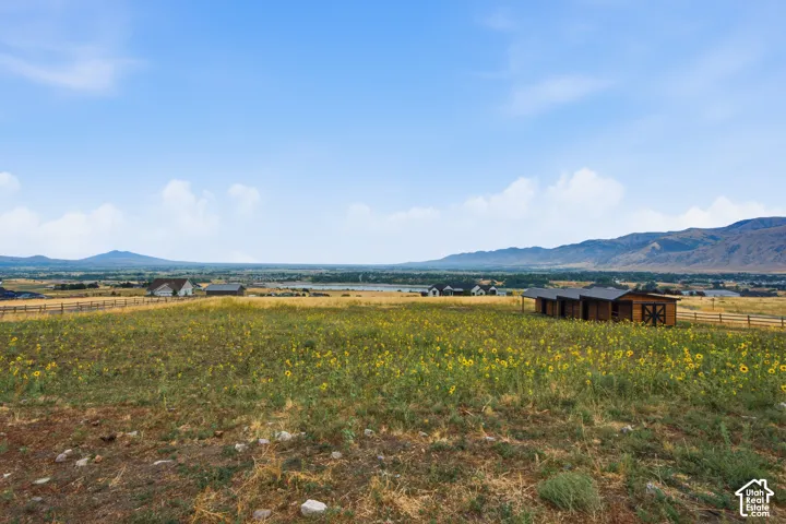 Expansive acreage featuring a natural landscape, mountain backdrop, wooden post-and-rail fencing, and a detached wood-sided outbuilding