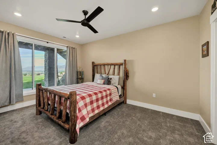 Neutral wall tones, carpeted flooring, recessed lighting, matte black ceiling fan, and large windows with mountain and landscape scenery