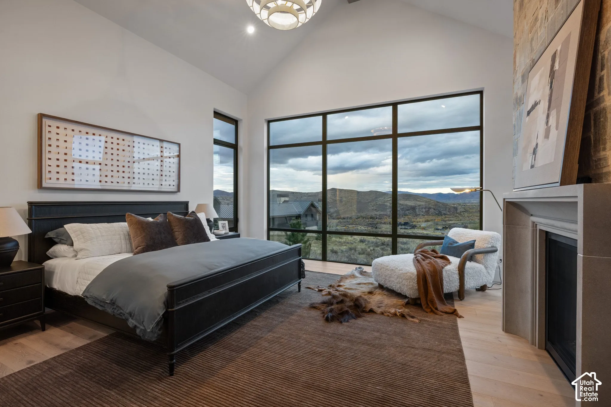 Vaulted ceilings, expansive floor-to-ceiling windows, stone-surround fireplace, and wood-finish flooring