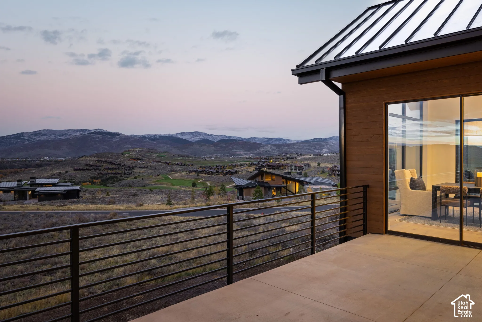 Covered concrete terrace featuring a metal cable railing, horizontal wood siding, metal roof, and floor-to-ceiling glass panel windows