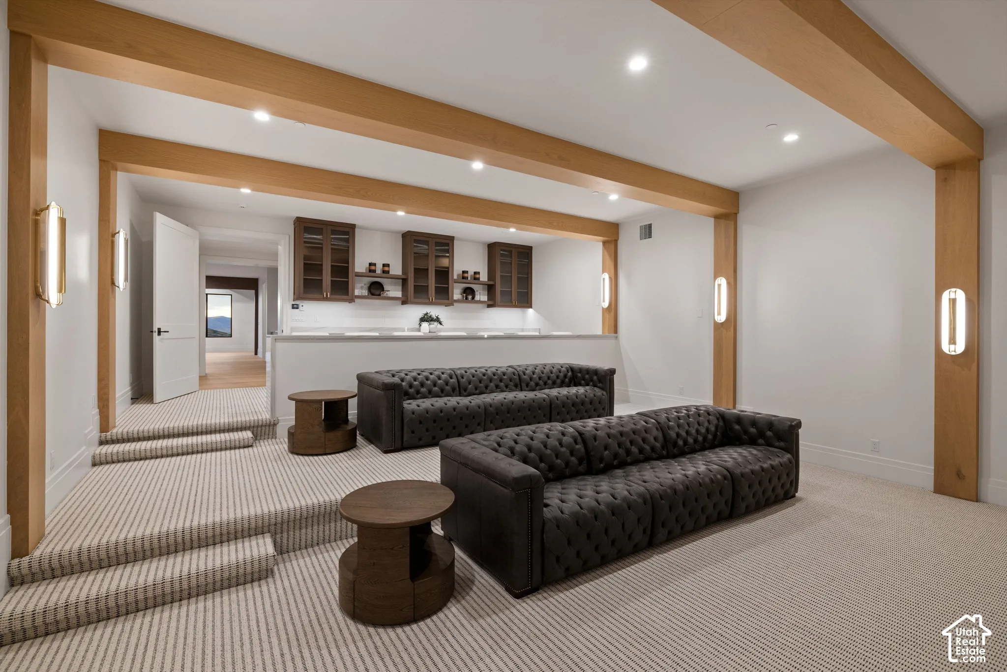 Sunken room featuring exposed natural wood beams, custom built-in cabinetry, wall-mounted vertical light fixtures, and carpeted flooring