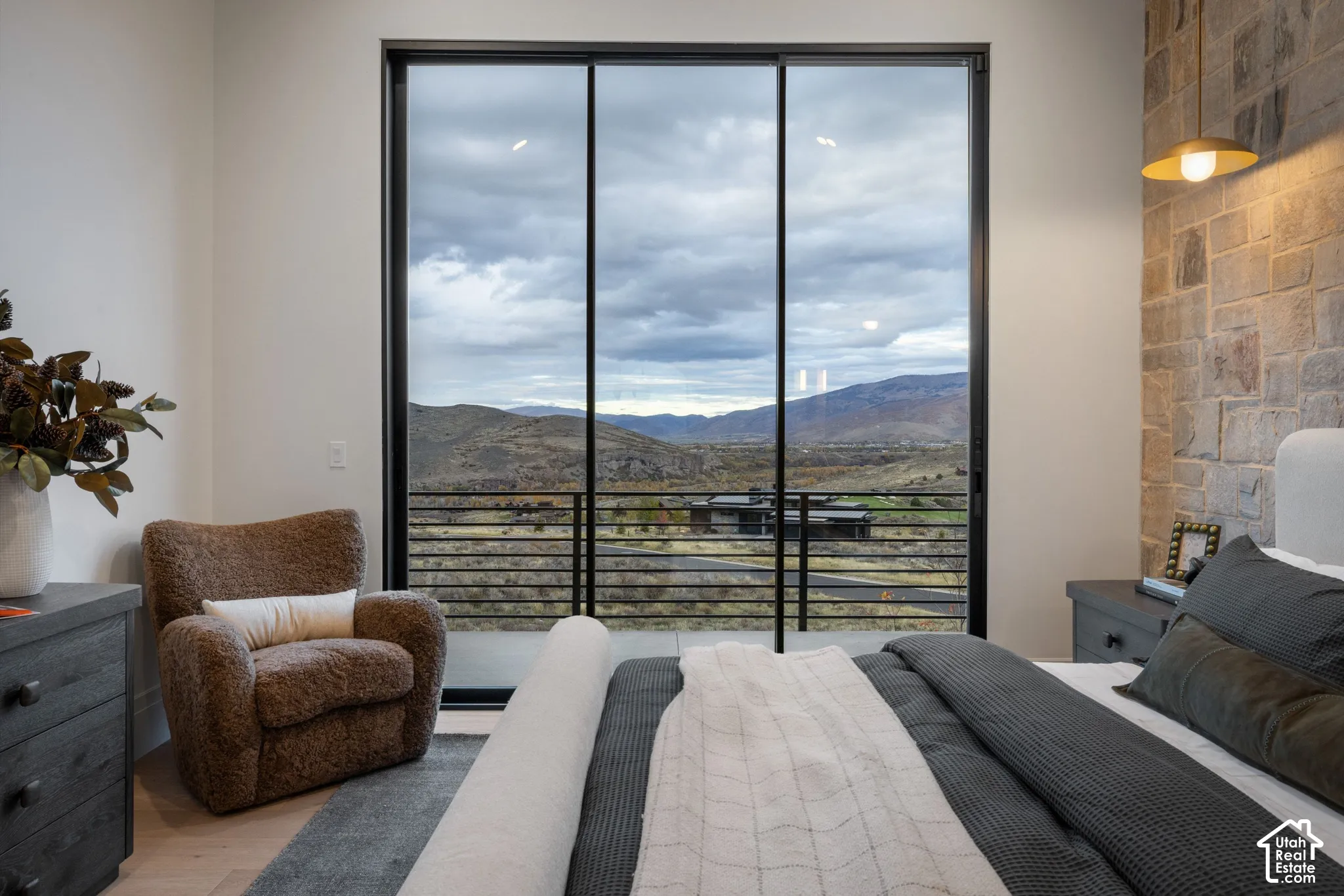 Floor-to-ceiling sliding glass door system, stone accent wall, metal cable railing, and pendant lighting